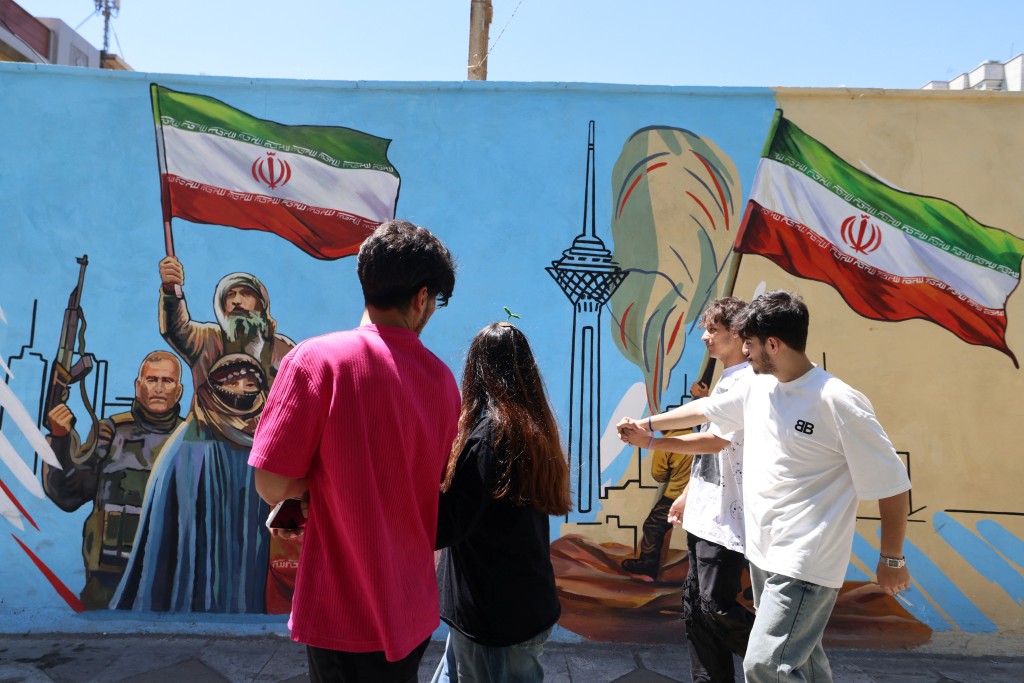 Photo by ATTA KENARE / AFP  Iranians walk past an anti-US and anti-Israel mural painted on a wall in the capital Tehran on May 10, 2026.