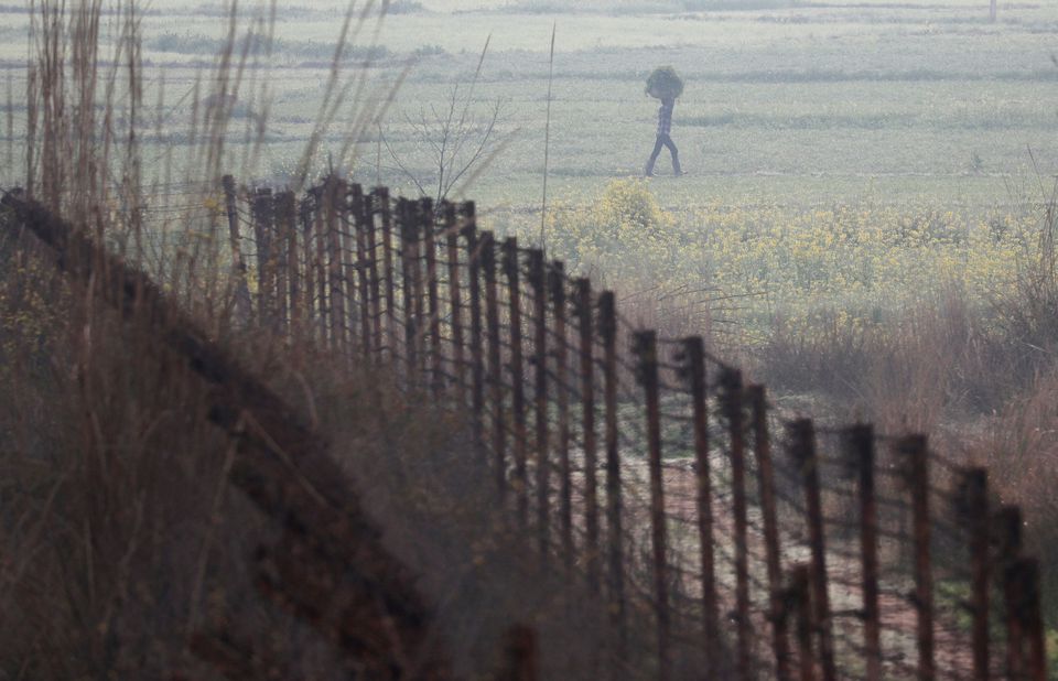 A farmer carries a sack of grass as he walks near the fenced border between India-Pakistan. (Reuters) A farmer carries a sack of grass as he walks near the fenced border between India-Pakistan. (Reuters)