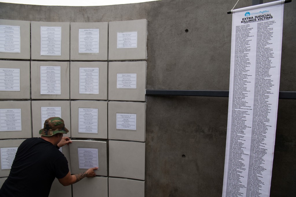 Photo by TED ALJIBE / AFP  A volunteer at the "Dambana ng Paghilom Center" (Shrine of Healing) fixes a closet where urns of victims of extrajudicial killings of former Philippine president Rodrigo Duterte's drug war are placed, during the inurnment rites at a cemetery in Caloocan city, suburban Manila on February 20, 2026. 