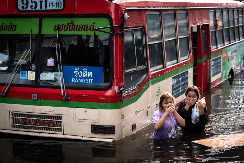 Photo by CHANAKARN LAOSARAKHAM / AFP Women walk past an abandoned bus in the Bang Kapi district of Bangkok on September 28, 2026.