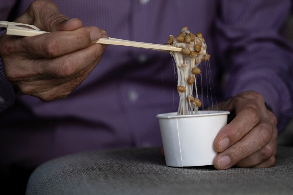 Photo by ANDREW CABALLERO-REYNOLDS / AFP This photo taken on May 15, 2026 shows Yoshihiro Noro, owner of the Kamakurayama Natto production facility, mixing natto at his store in Kamakura, Kanagawa prefecture.