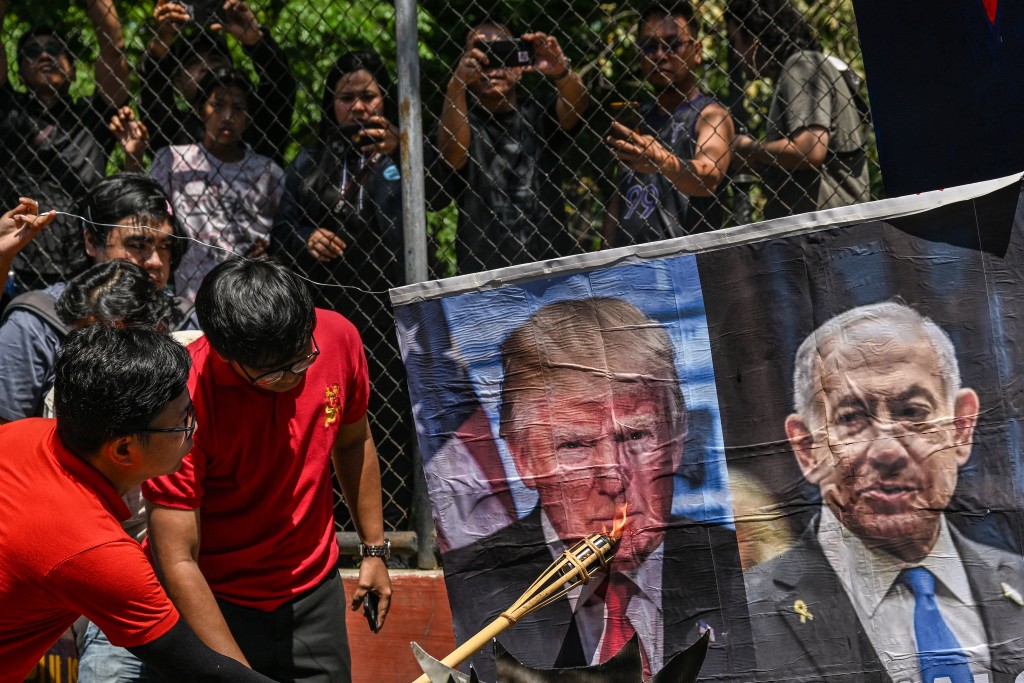 A man burns a picture of US President Donald Trump and Israeli Prime Minister Benjamin Netanyahu during a protest against the US-Israel military action in Iran, near the US Embassy in Manila on April 9, 2026. (AFP)