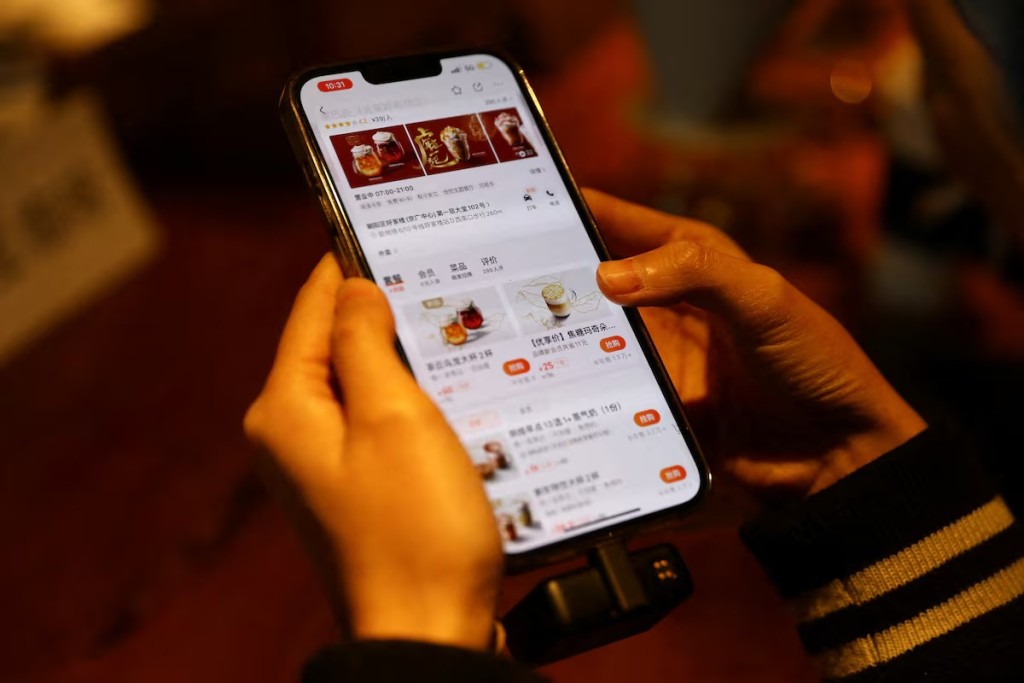 A journalist checks the Starbucks menu on the Meituan app on her phone, at a Starbucks flagship store in Beijing, China January 18, 2022. REUTERS