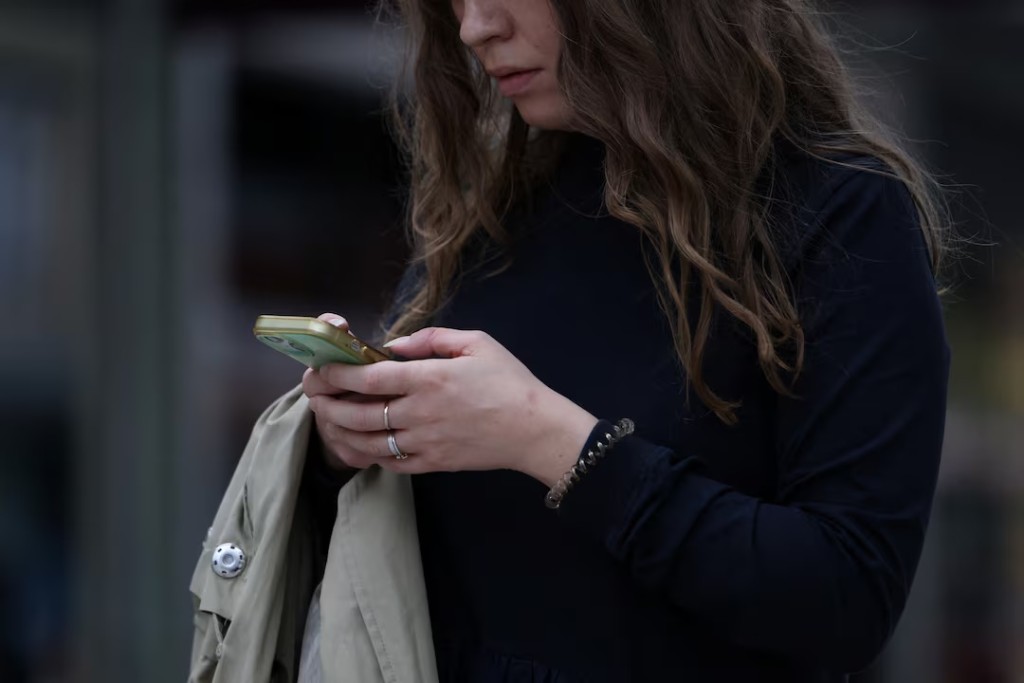 A woman uses a smartphone in London, Britain, October 6, 2024. REUTERS/Hollie Adams
