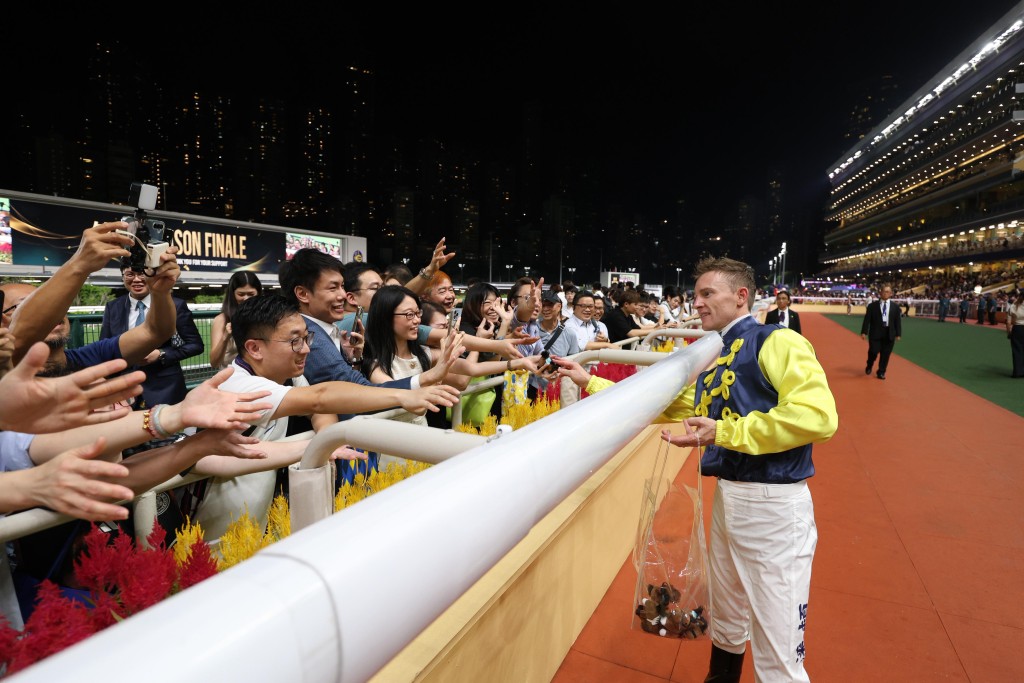 Jockey Zac Purton hands out souvenirs to racegoers. (Sing Tao)