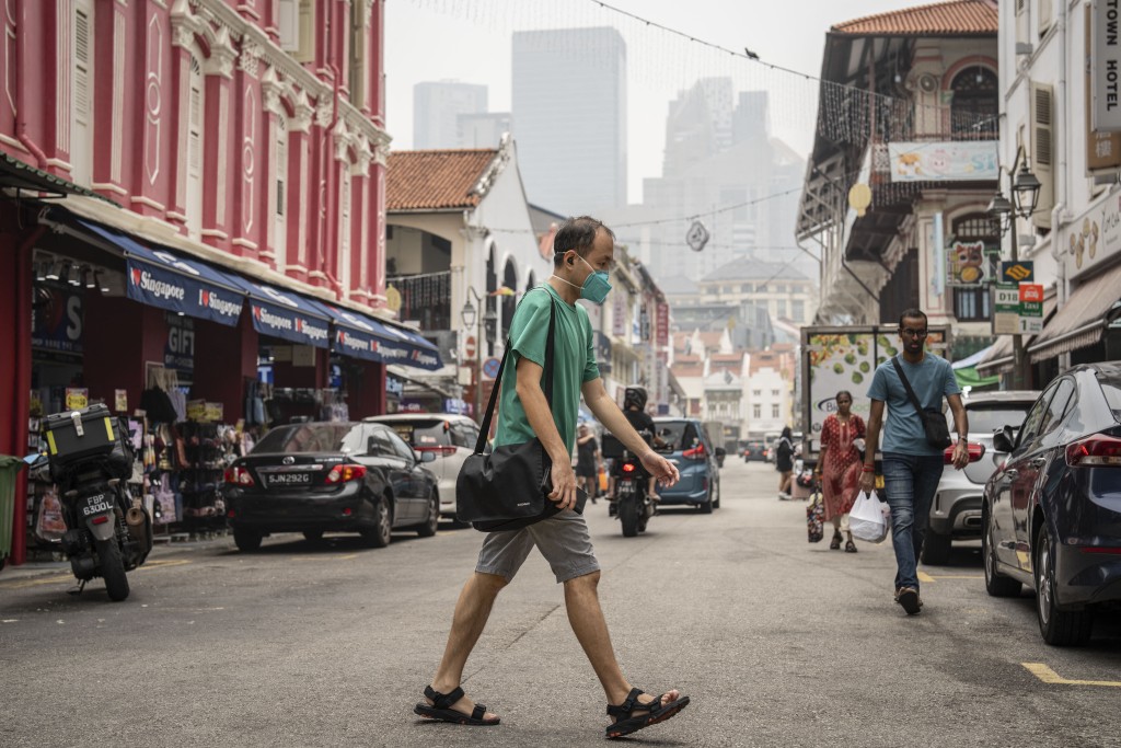 Photo by YUICHI YAMAZAKI / AFP A man wearing a face mask crosses a street in Singapore's Chinatown on October 17, 2026, as the country continues to be shrouded in haze caused by fires in Indonesia.