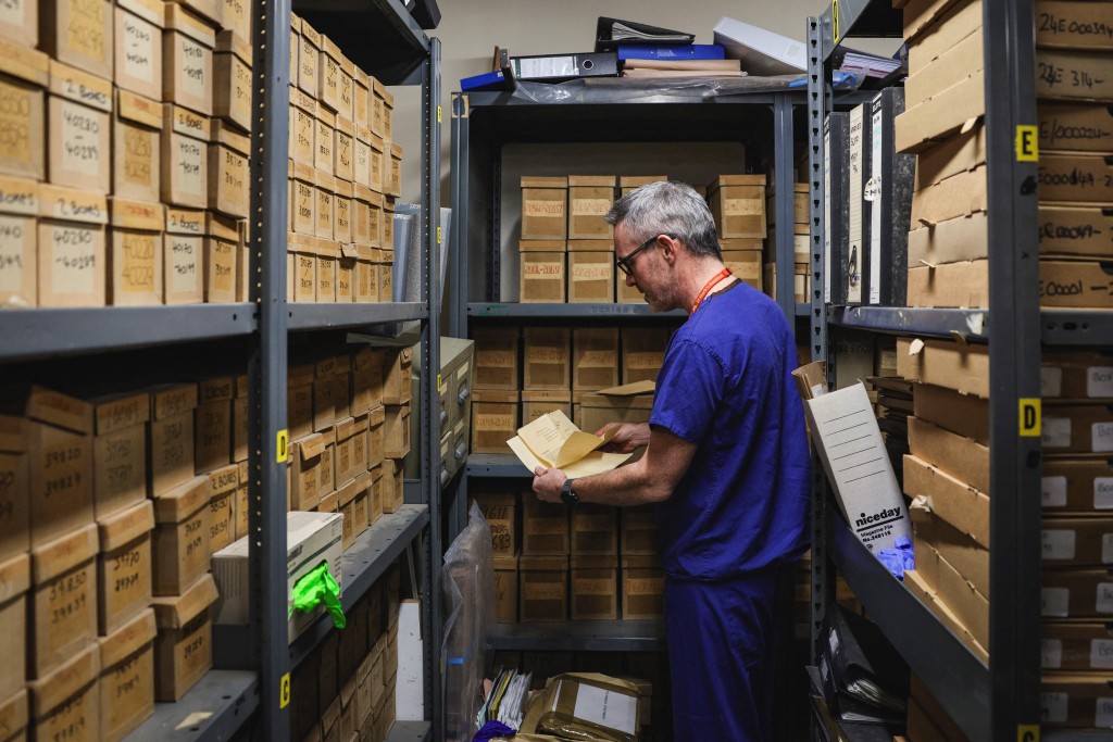 Photo by ADRIAN DENNIS / AFP  This photo taken on January 14, 2026 shows consultant gastroenterologist Kevin Monahan looking through samples in a storeroom at St Mark’s hospital at Northwick Park in Harrow, west London.