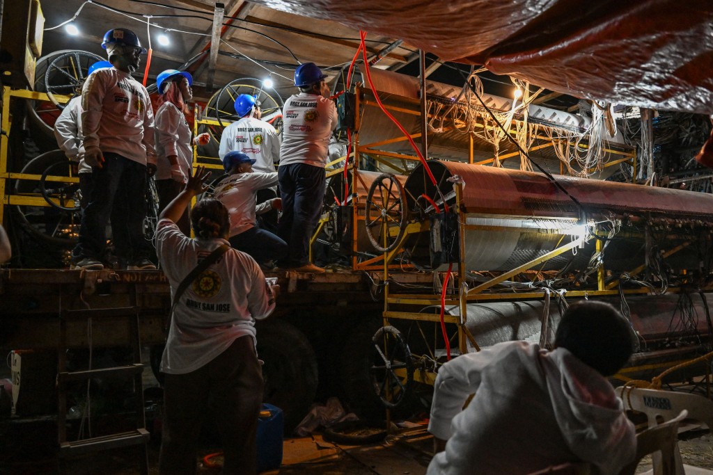 Photo by JAM STA ROSA / AFP  This photo taken on December 14, 2025, shows men working on the lights behind the giant lantern during the Giant Lantern Festival in San Fernando, Pampanga.
