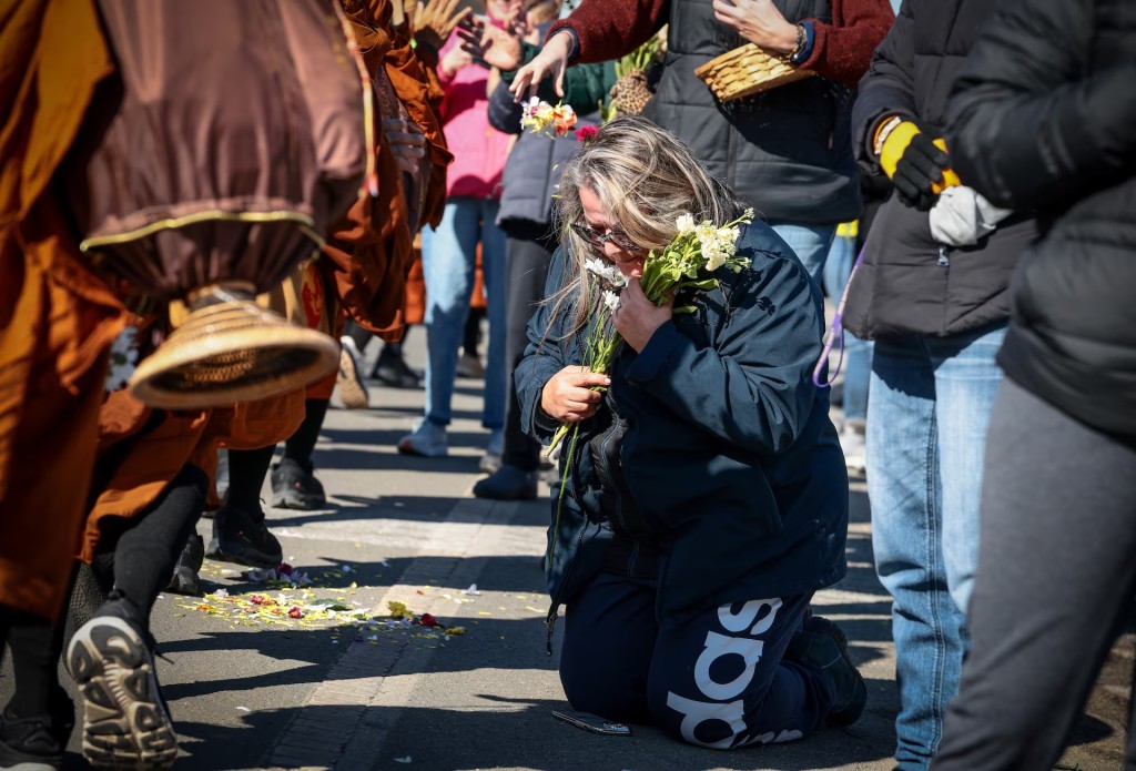 A woman kneels on the side of the road as a group of Buddhist monks pass during the "Walk for Peace" in Spotsylvania, Virginia, February 5, 2026. REUTERS/Evelyn Hockstein