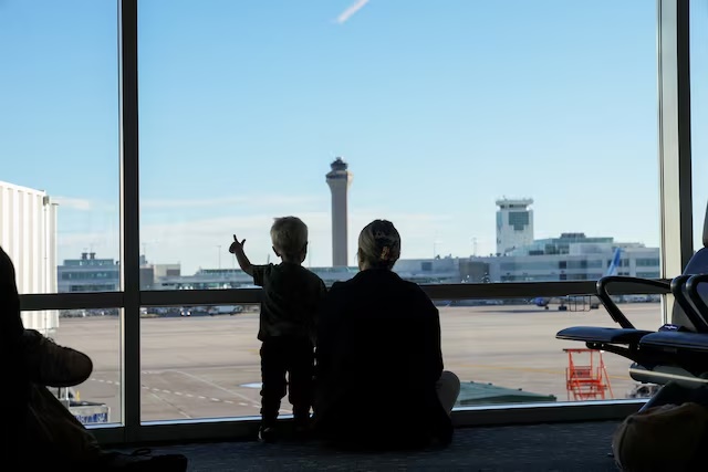 The air traffic control tower is seen from the gate as a woman and a child look out at the Denver International Airport terminal, in Denver, Colorado, U.S., May 15, 2025. REUTERS/Megan Varner