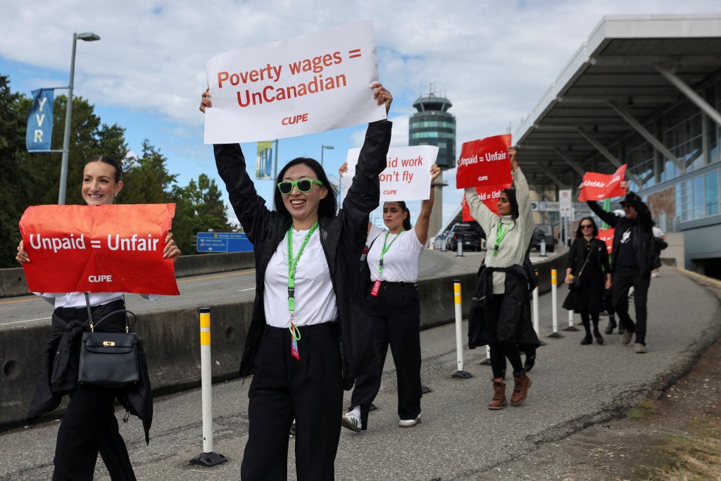 Demonstrators hold placards on the day the strike begins, after the union representing more than 10,000 of Air Canada's flight attendants failed to reach an agreement with the airline, at Vancouver International Airport in Richmond, British Columbia, Canada, August 16, 2025. REUTERS/Chris Helgren REFILE - QUALITY REPEAT