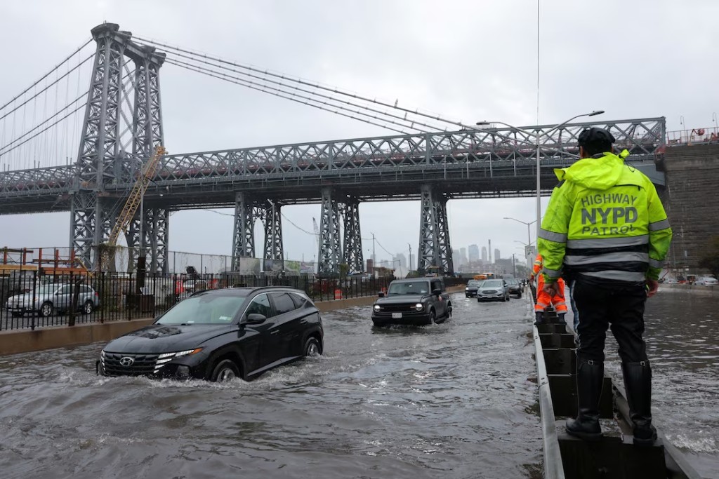  A police officer from the NYPD Highway Patrol looks to motorists drive through a flooded street after heavy rains as the remnants of Tropical Storm Ophelia bring flooding across the mid-Atlantic and Northeast, at the FDR Drive in Manhattan near the Williamsburg Bridge, in New York City, U.S., September 29, 2023. REUTERS/Andrew Kelly/ File Photo 