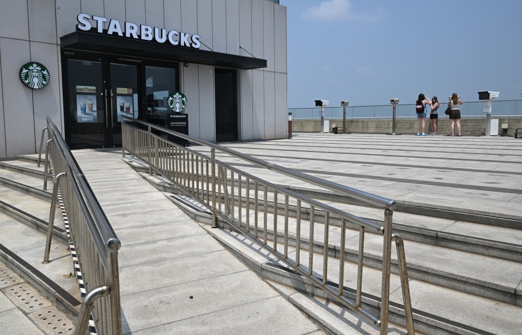 Photo by JUNG YEON-JE / AFP  Visitors stand next to a Starbucks store to watch the North Korean side from a South Korean observation deck at Aegibong Peace Ecopark in Gimpo on July 1, 2026.