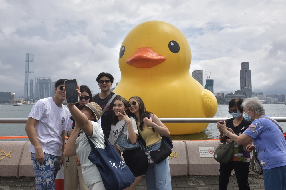 People take selfies after queueing to see the floating giant. Below: mini ducks in Ngong Ping and Florentijn Hofman with the reinflated second duck. SING TAO
