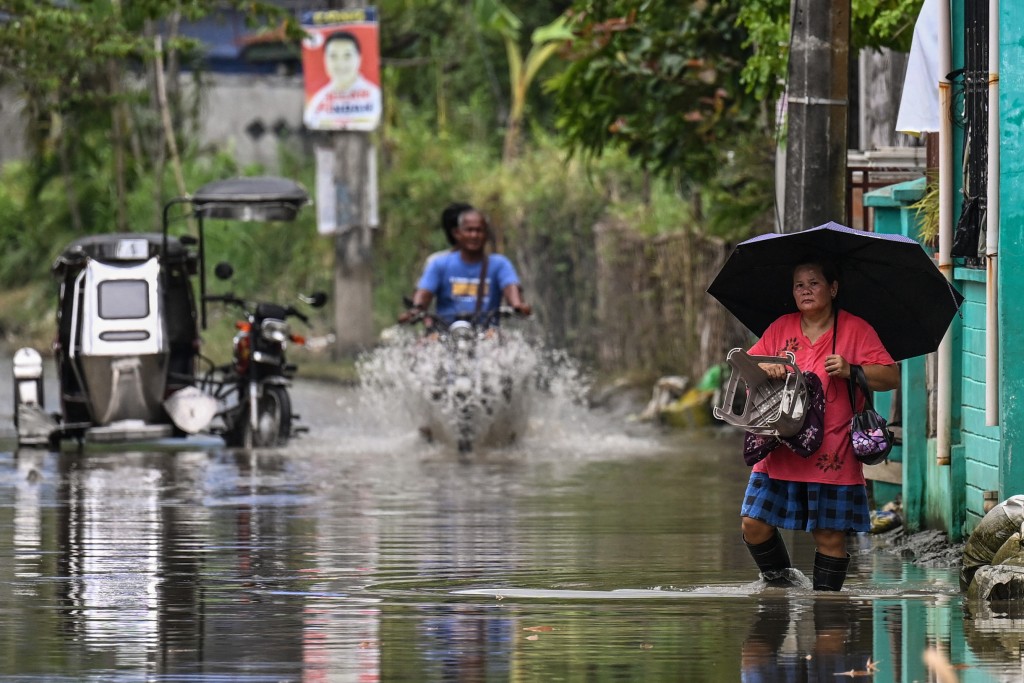 In this photo taken on September 15, 2025, residents wade through a flooded area in Calumpit, Bulacan. More than 100 flood-control projects are at the centre of the country's biggest corruption scandal in decades. (Photo by Jam STA ROSA / AFP)