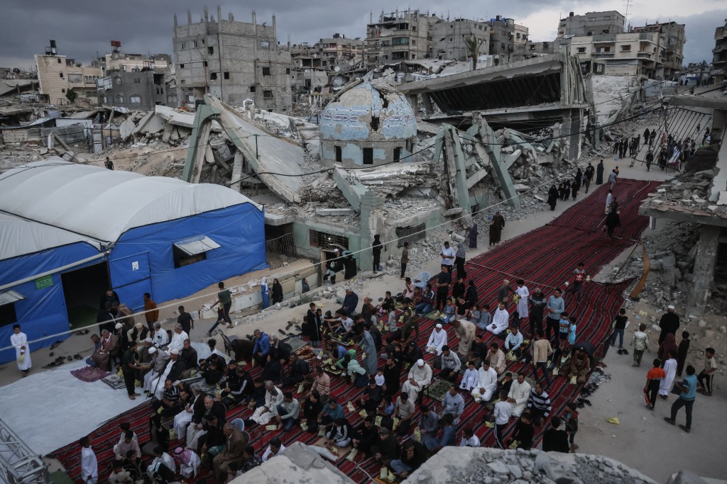 Photo by BASHAR TALEB / AFP  Palestinians gather on a heavily damaged street to perform morning prayers marking the start of Eid al-Adha, the Feast of Sacrifice, in Khan Yunis in the southern Gaza Strip on May 27, 2026.