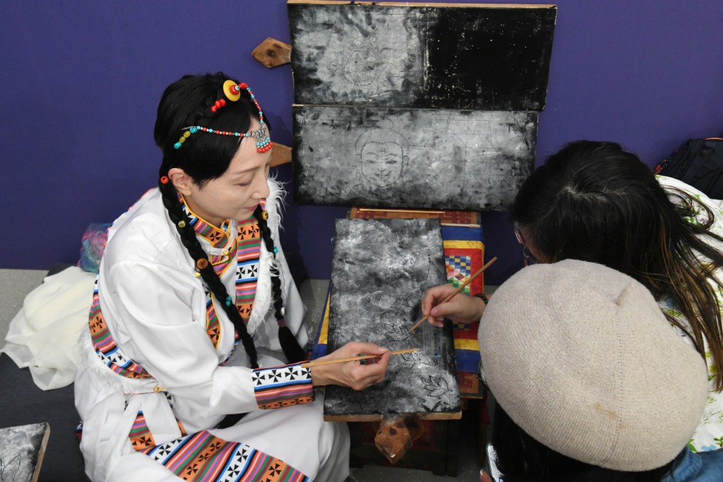 A thangka painter teaches techniques in a workshop, which is part of the exhibition.