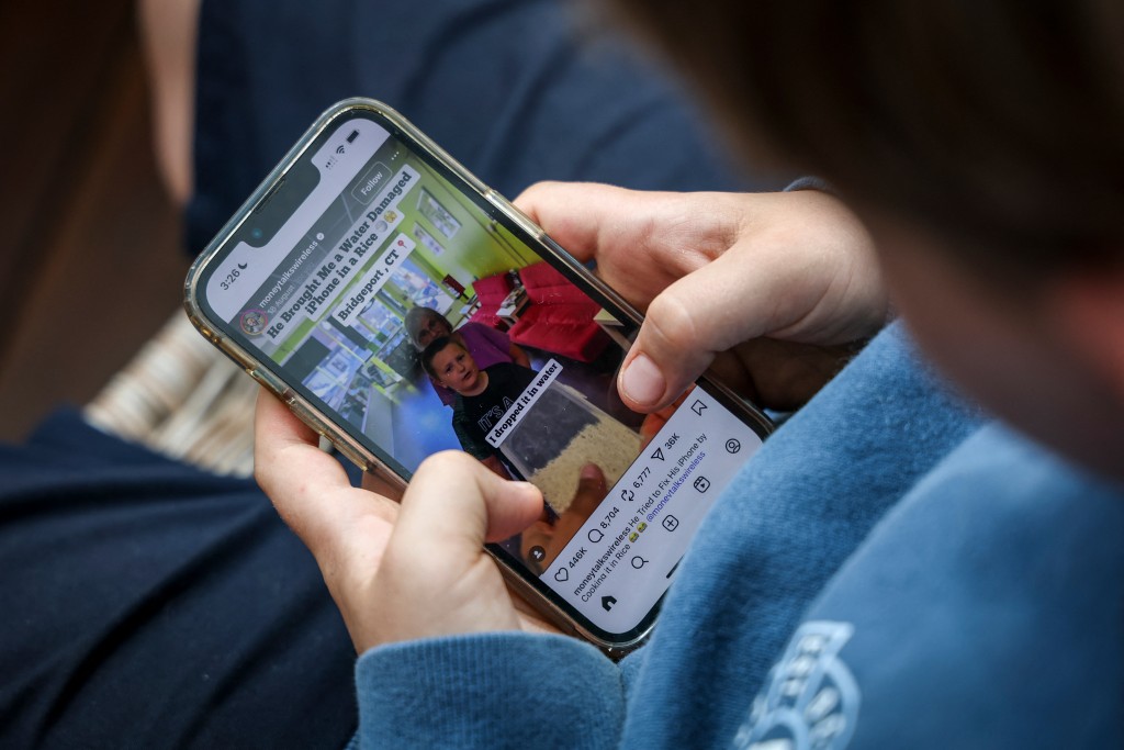 Photo by DAVID GRAY / AFP  This photo taken on October 24, 2025 shows a 14-year-old boy posing at his home near Gosford as he looks at the Instagram app on his mobile phone.