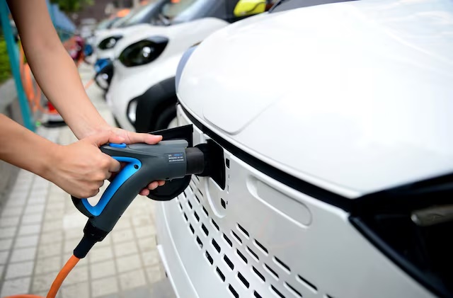 A staff member hooks up a charging cable to an electric vehicle (EV) at a charging station in Liuzhou, Guangxi Zhuang Autonomous Region, China July 31, 2017. REUTERS/Stringer