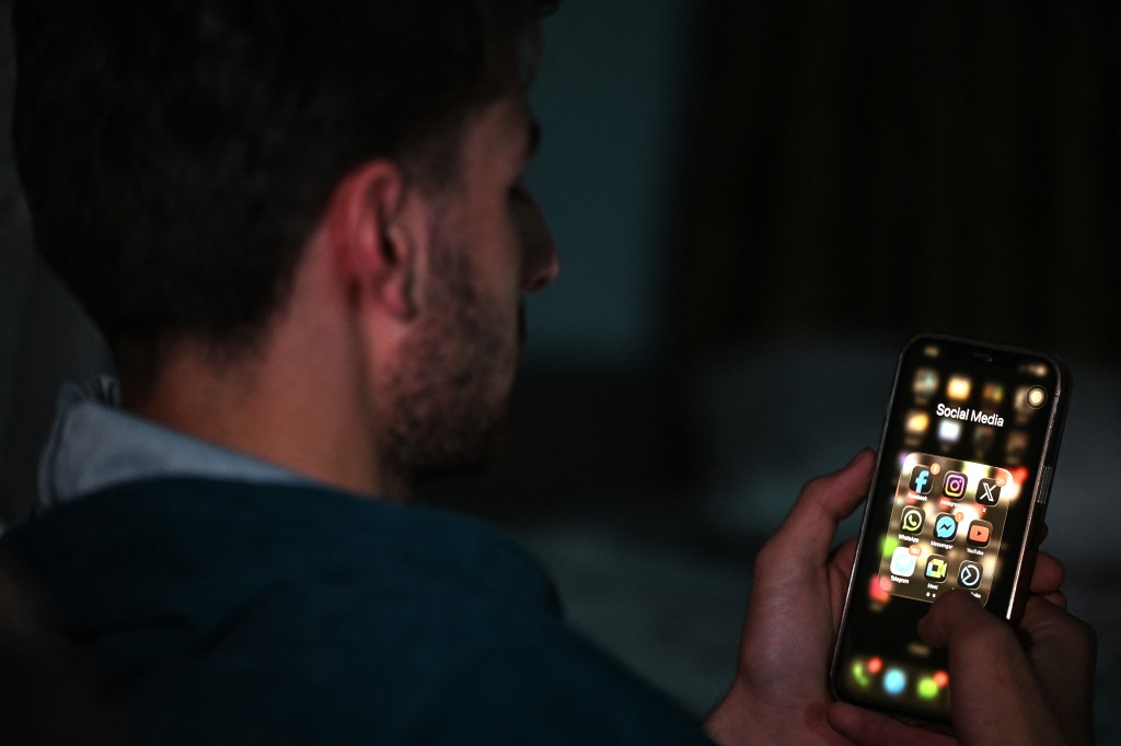 An Afghan student uses his mobile phone at his residence in Kabul on October 8, 2025. Access to several social media sites, including Facebook, Instagram and Snapchat, has been "intentionally restricted" in Afghanistan, an internet watchdog said on October 8, a week after a 48-hour telecommunications blackout in the country. (Photo by Wakil Kohsar / AFP)