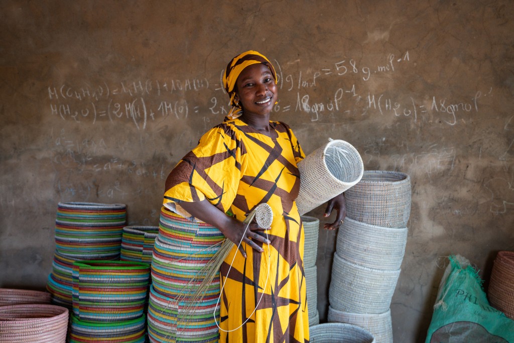 Photo by NICOLAS REMENE / AFP  Khady Sene, 35, poses for a portrait with a Senegalese handicraft basket at her house in Mborine, on 12 November 2025.