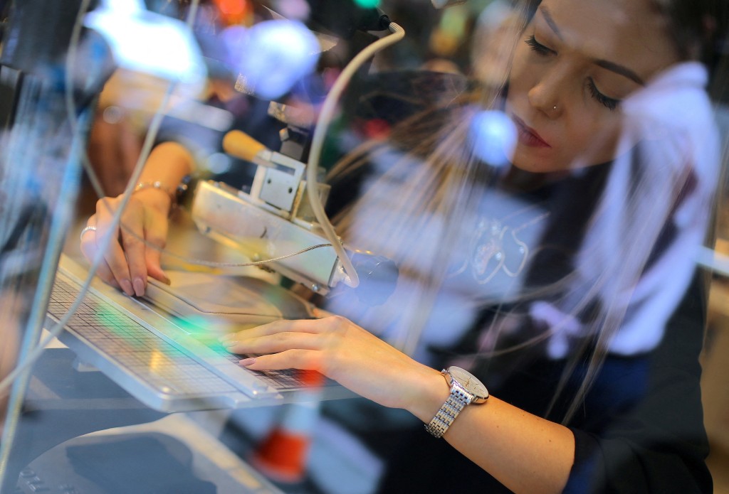 A woman uses a machine to emboss a wallet in the window of a retail store selling leather goods in central Sydney, Australia. (Reuters/File)