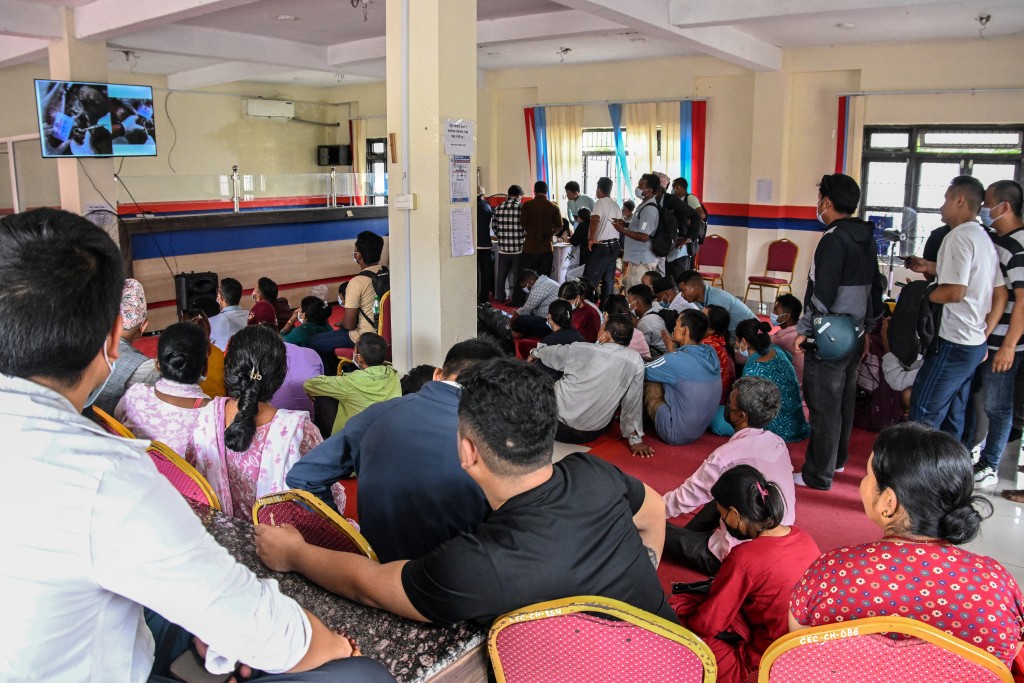 Photo by PRAKASH MATHEMA / AFP. Family members watch a screen displaying identities of victims at a mortuary in the aftermath of flash floods, in Bharatpur of Nepal's Chitwan district on August 30, 2026.