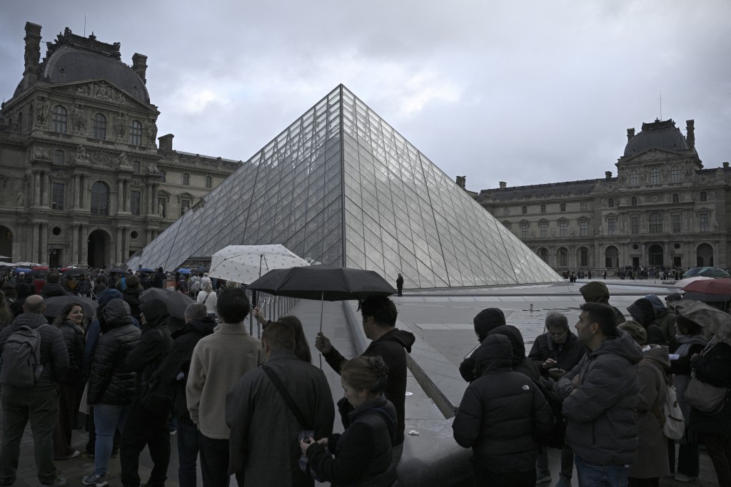 People queue in the Louvre pyramid courtyard moments before the announcement the museum will remain closed for a second day running after thieves stole crown jewels from the museum in Paris a day earlier, in Paris on October 20, 2025. (AFP)