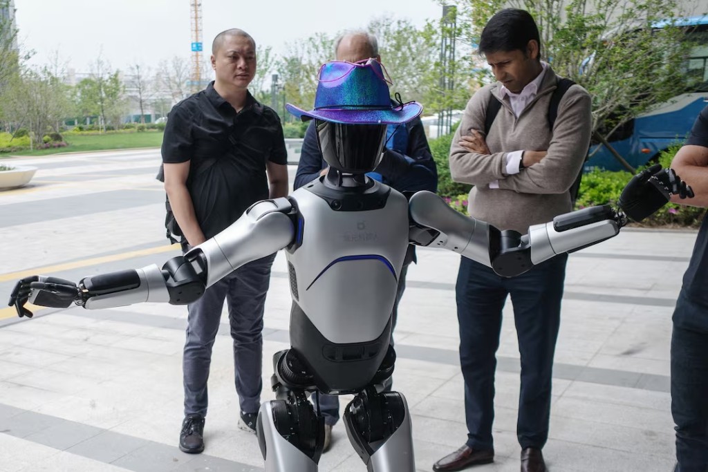 People interact with an Agibot RAISE A1 humanoid robot during a tour for foreign investors at the company's headquarters in Shanghai, China, April 20, 2026. REUTERS/Laurie Chen