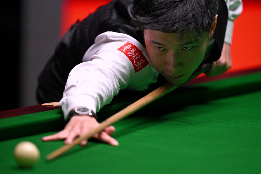 Photo by OLI SCARFF / AFP  China's Zhao Xintong plays a shot on day two of his World Championship Snooker final against Wales' Mark Williams during the afternoon session at The Crucible in Sheffield, northern England on May 5, 2025.