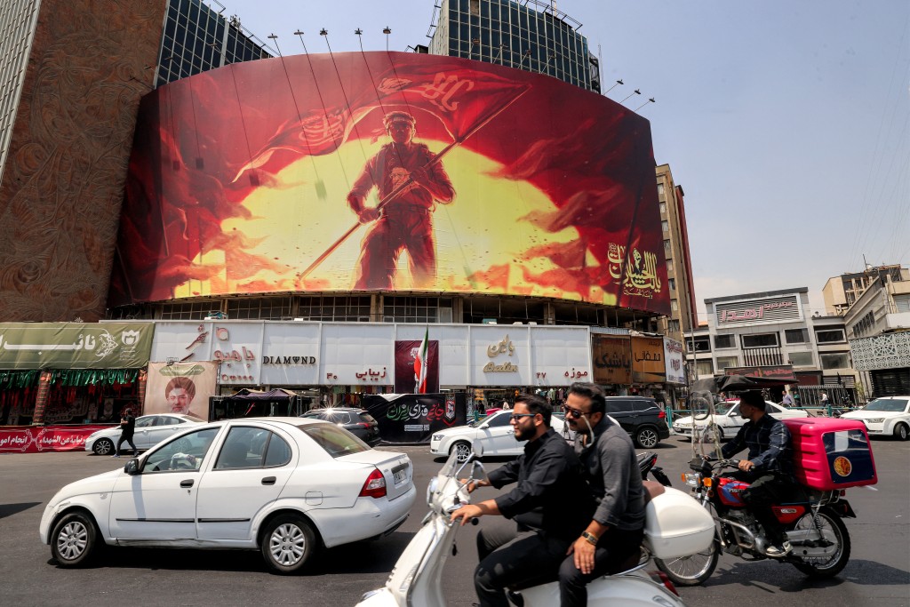 Motorists drive past a political billboard at Valiasr Square in central Tehran. (AFP)