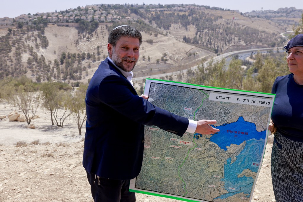 Israeli far-right Finance Minister Bezalel Smotrich displays a map of an area near the settlement of Maale Adumim, a land corridor known as E1, outside Jerusalem in the occupied West Bank, on August 14, 2025, after a press conference at the site. Far-right ministers have in recent months openly called for Israel's annexation of the territory. Plans exist to build more than 3,000 housing units, schools, health clinics and a country club on E1 between Maale Adumim and Jerusalem. Photo by Menahem Kahana / AFP