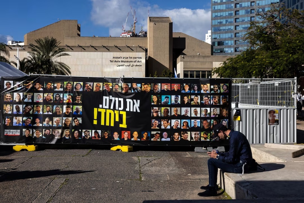 A man sits next to pictures of hostages kidnapped during the deadly October 7, 2023 attack by Hamas, at the so-called A man sits next to pictures of hostages kidnapped during the deadly October 7, 2023 attack by Hamas, at the so-called