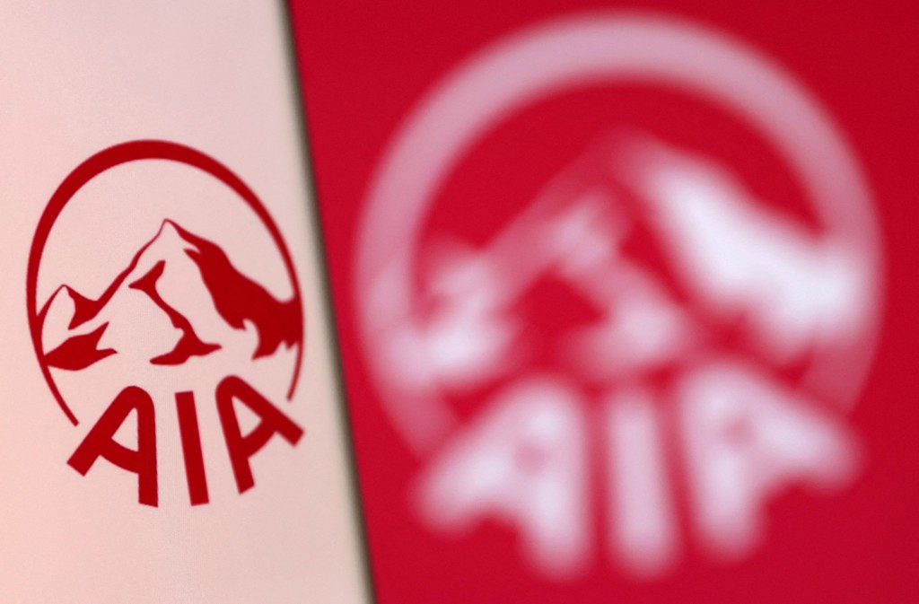 AIA Group logo is pictured on a smartphone in front of an electronic display showing the same logo in this illustration taken, December 4, 2021. REUTERS