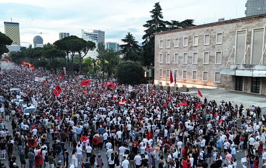 Photo by ADNAN BECI / AFP  An aerial photograph taken on June 11, 2026 shows protestors holding placards and national flags during a demonstration in front of Albania Prime Minister's Office, in Tirana, to protest against the construction of a luxury resort near a protected natural area of Zvernec near Vlore.