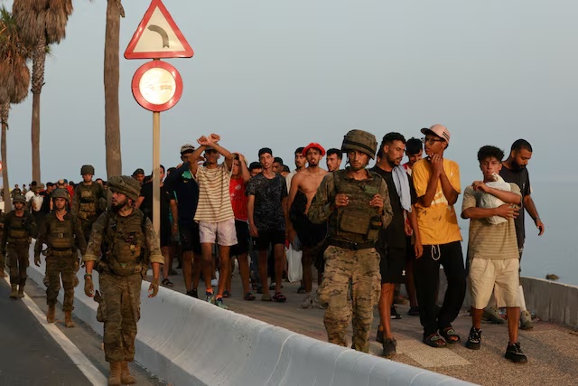Members of the military escort migrants in Ceuta, Spain, following recent mass crossings of migrants on foot and by sea from Morocco into Spanish territory, August 1, 2026. REUTERS/Violeta Santos Moura 