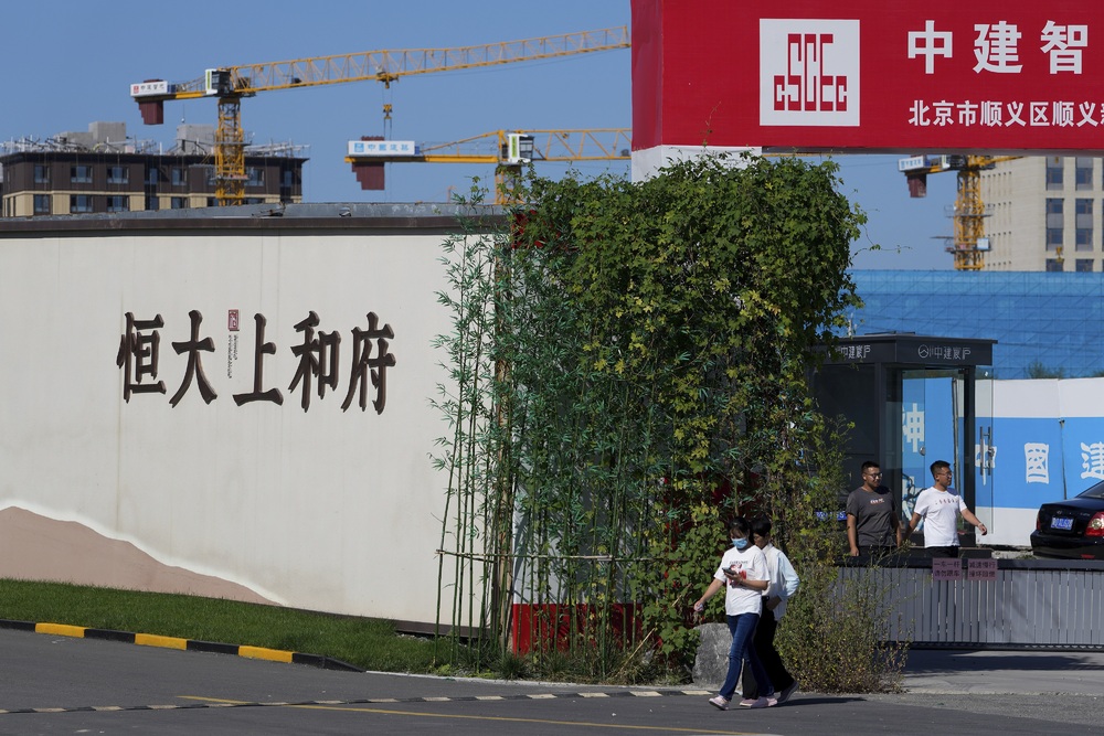 People walk out from an Evergrande new housing development in Beijing. (AP) People walk out from an Evergrande new housing development in Beijing. (AP)