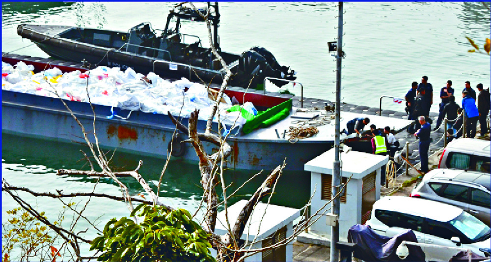 Inspectors check the suspected smuggling vessel, which was carrying frozen meat, as the flipped patrol boat floats near the pier. SING TAO Inspectors check the suspected smuggling vessel, which was carrying frozen meat, as the flipped patrol boat floats near the pier. SING TAO