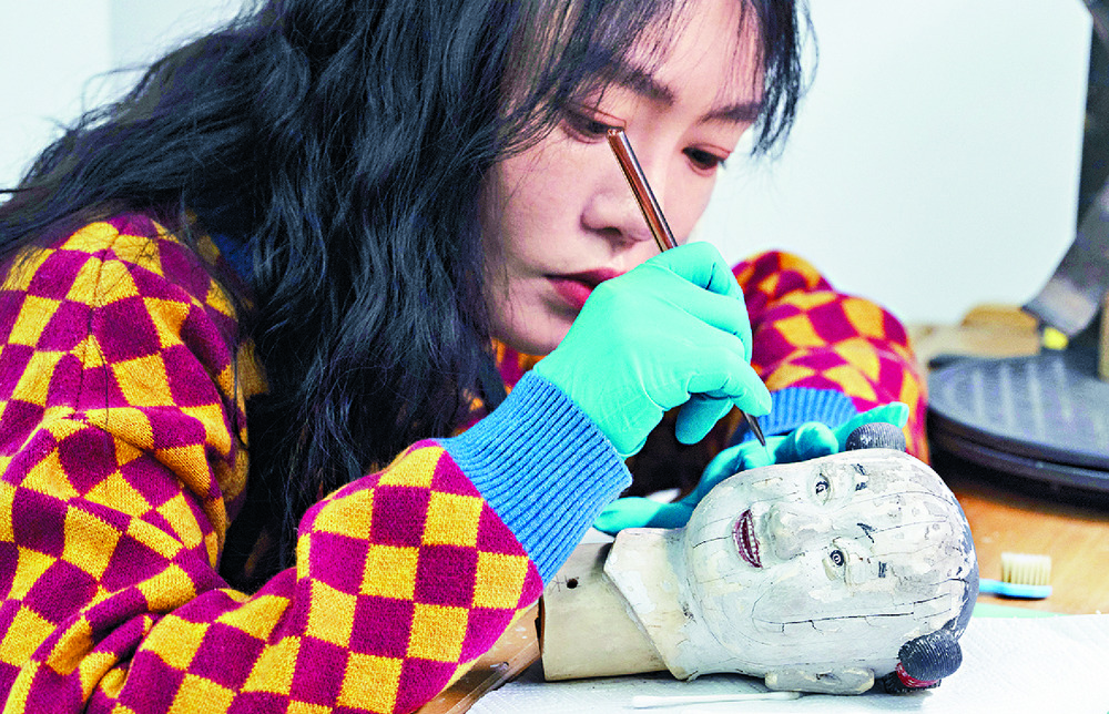 Restorers work on the head of a mechanical doll, an antique painting and the mechanism of an antique clock in a restoration workshop on the sprawling compound of the Forbidden City. AP