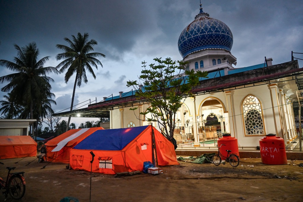 Photo by CHAIDEER MAHYUDDIN / AFP  Tents used as temporary housing by flood survivors are seen beside a mosque in Meurah Dua, Aceh province's Pidie Jaya district on February 21, 2026, after devastating floods and landslides struck Indonesia's Sumatra late last year.