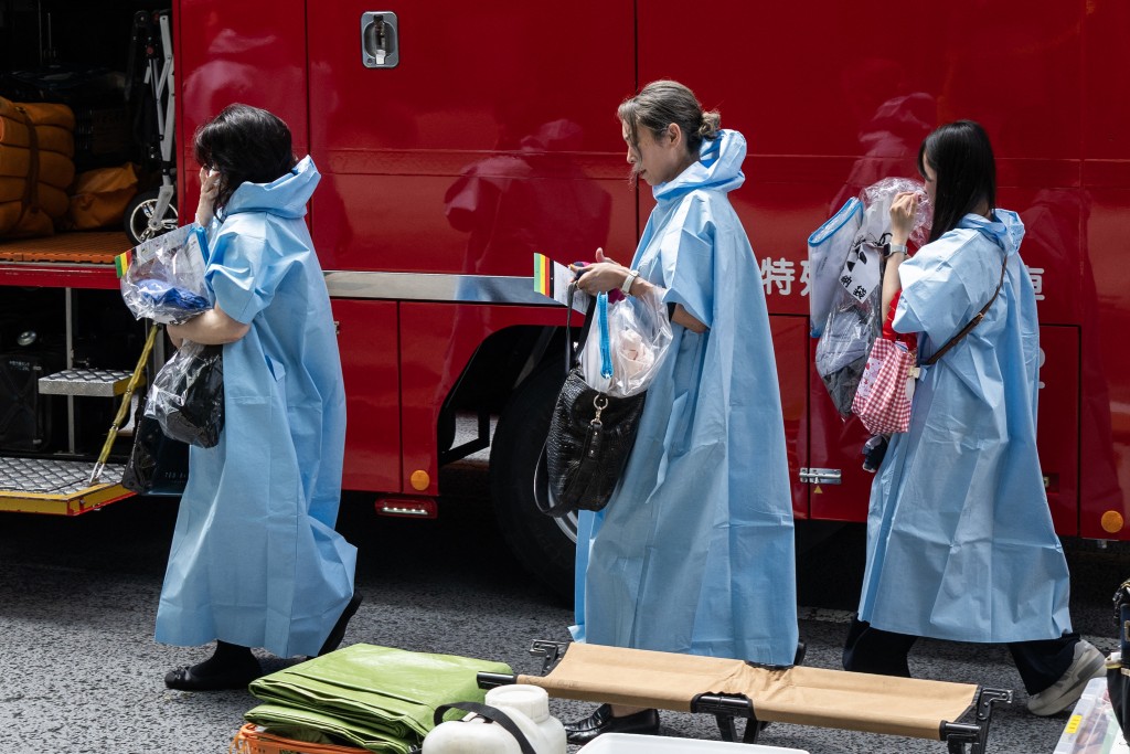 Women that were inside the Ginza 6 Shopping Center walk past an emergency emergency vehicle in Tokyo on May 25, 2026, after an individual allegedly sprayed a substance in the area. (AFP)