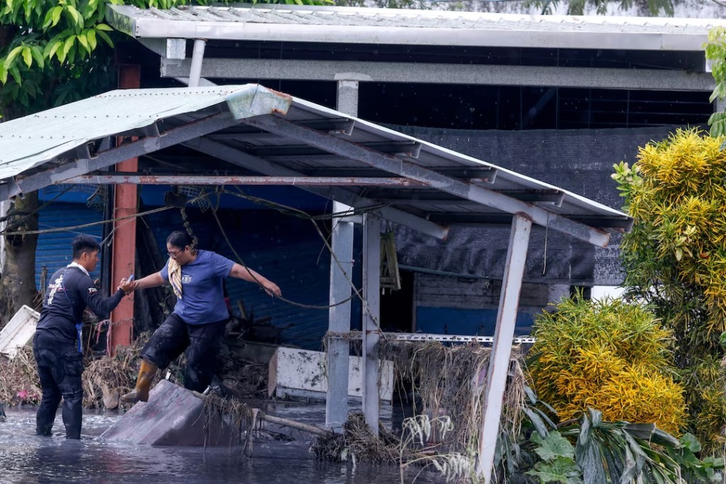 A firefighter helps a resident evacuate through floodwaters after Super Typhoon Ragasa in Hualien, Taiwan, September 26, 2025. REUTERS/Ann Wang 