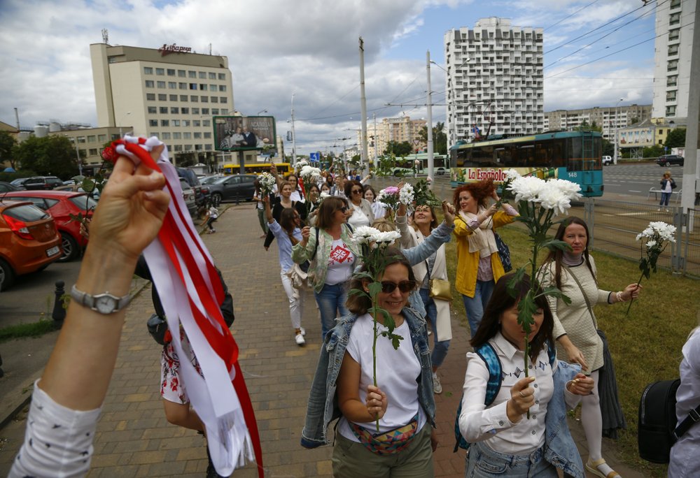 A Belarusian woman shows a white-and-red ribbon symbol of protest while others carry flowers on a rally in solidarity with protesters injured in the latest rallies against the results of the country's presidential election in Minsk, Belarus.