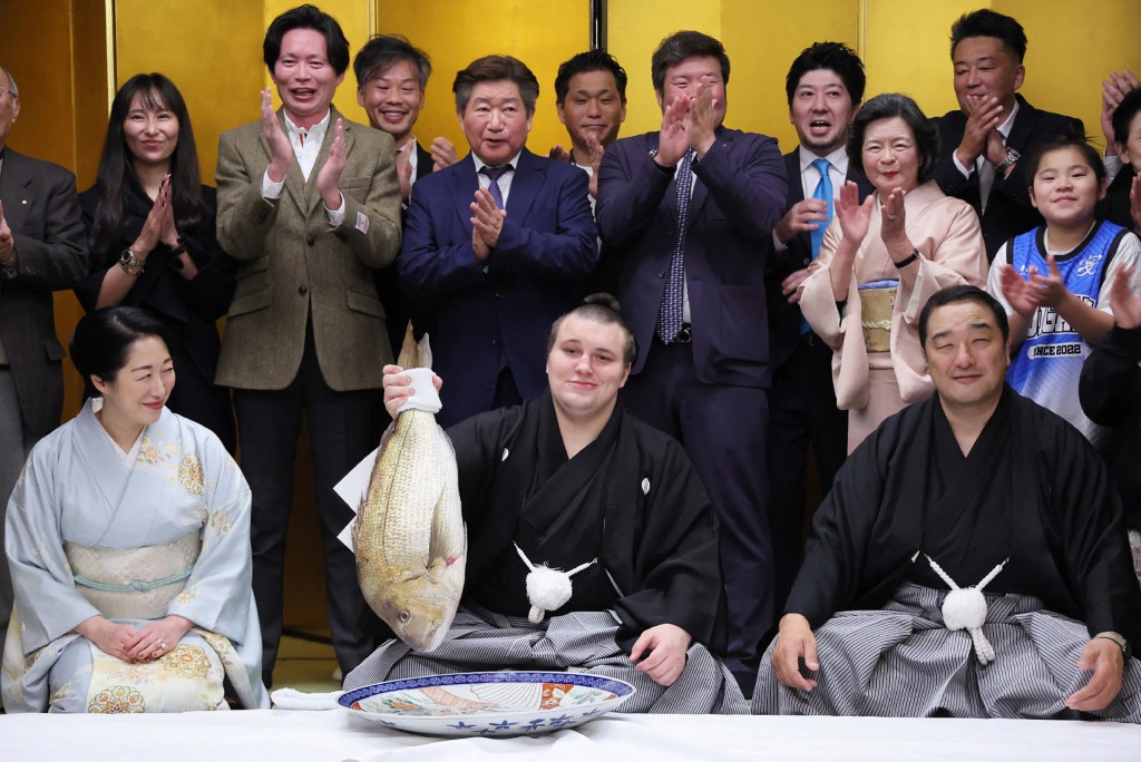 Photo by STR / JIJI PRESS / AFP  Ukrainian sumo wrestler Danylo Yavhusishyn (front C), also known by his Japanese ring name Aonishiki Arata poses with a seabream to celebrate after winning the Grand Sumo Tournament in Kurume city of Fukuoka Prefecture on November 23, 2025.