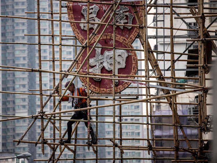A scaffolder constructing bamboo scaffolding around a neon sign. (AFP) A scaffolder constructing bamboo scaffolding around a neon sign. (AFP)