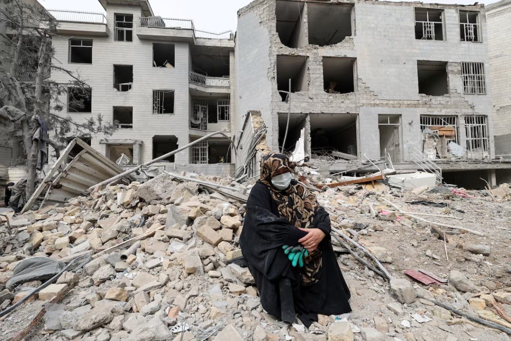 A woman sits outside her destroyed apartment after it was damaged by an airstrike while she was inside, amid the U.S.-Israeli conflict with Iran, in Tehran, Iran, March 12, 2026. REUTERS/Alaa Al Marjani 