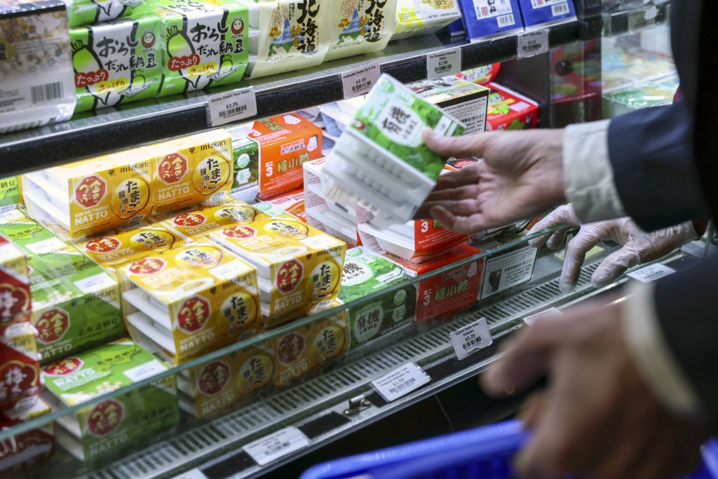 Photo by ANGELA WEISS / AFP This photo taken on May 8, 2026 shows a shopper picking up packages of natto, fermented soybeans, at a Japanese grocery store in the Manhattan borough of New York City.