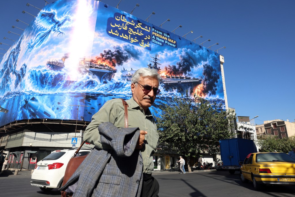 Photo by - / AFP Iranians walk past a huge anti-US billboard reading in Persian, ‘The devil army will be drowned in the Persian Gulf’, erected on Enghelab Square in Tehran on September 23, 2026.