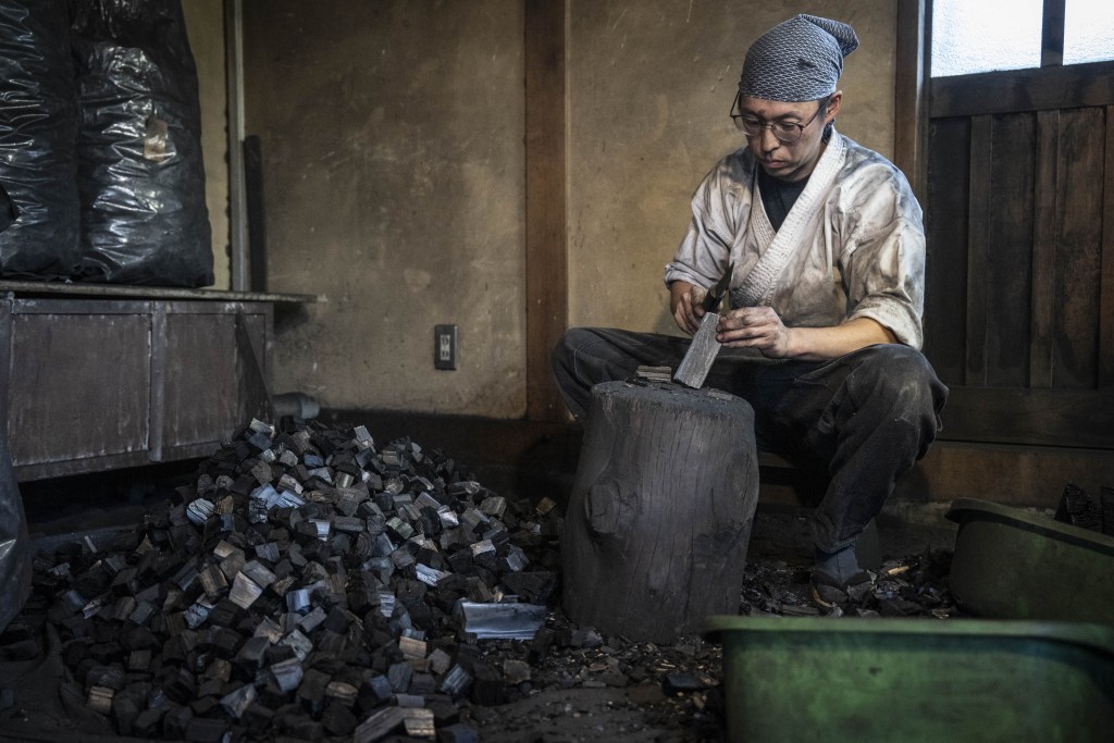 Photo by YUICHI YAMAZAKI / AFP  This picture taken on January 9, 2026 shows swordsmith Akihira Kawasaki's apprentice Toru Watanabe breaking charcoal into smaller pieces at Kawasaki's workshop in Misato, Saitama prefecture.