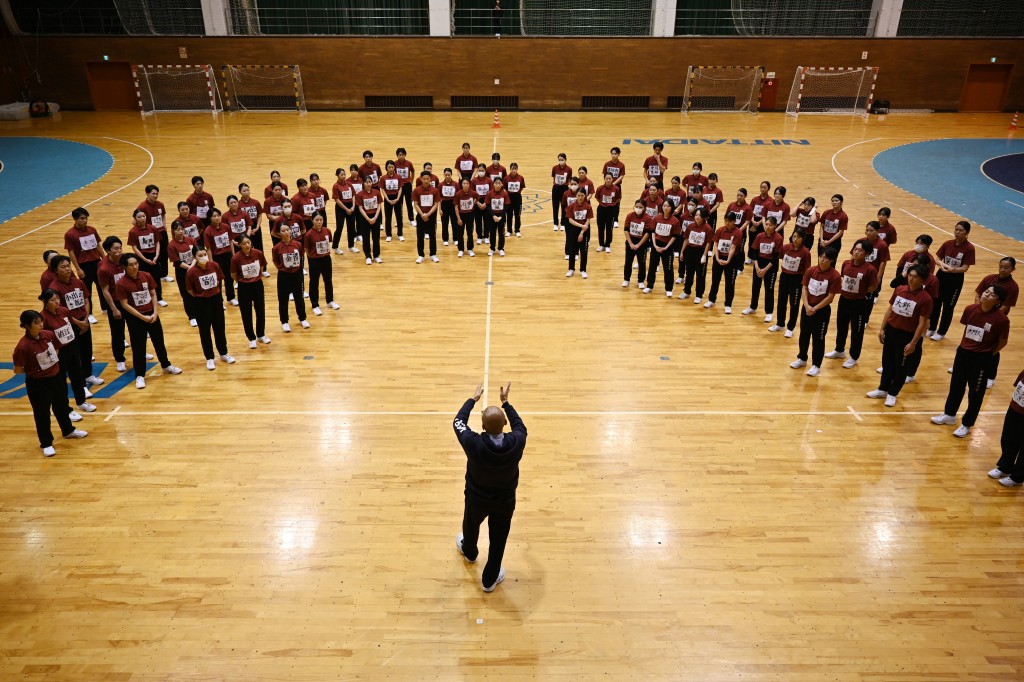 Photo by GREG BAKER / AFP  Coach Jiro Omi talks to students of Nippon Sports Science University during rehearsals for their annual synchronised walking performance, known as Shudankodo, in Yokohama on November 26, 2025.